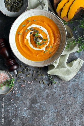 Pumpkin and carrot soup served with cream and seeds. Top view with copy space. Healthy food.