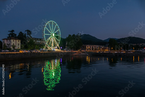 Ferris wheel illuminated in the evening with the lights reflecting on the Lake Maggiore in Luino