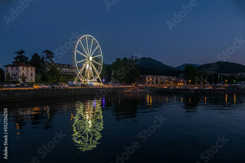 Ferris wheel illuminated in the evening with the lights reflecting on the Lake Maggiore in Luino