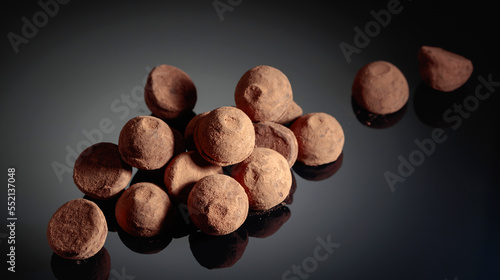 Chocolate truffles on a black reflective background.