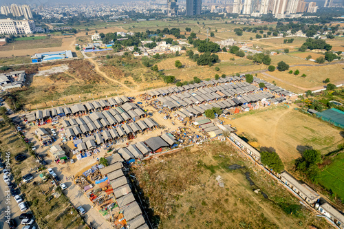 aerial drone decending shot of banjara market in gurgaon delhi showing disorganized temporary tents houses in slums showing this famous handicraft and furniture market surrounded by cars parked