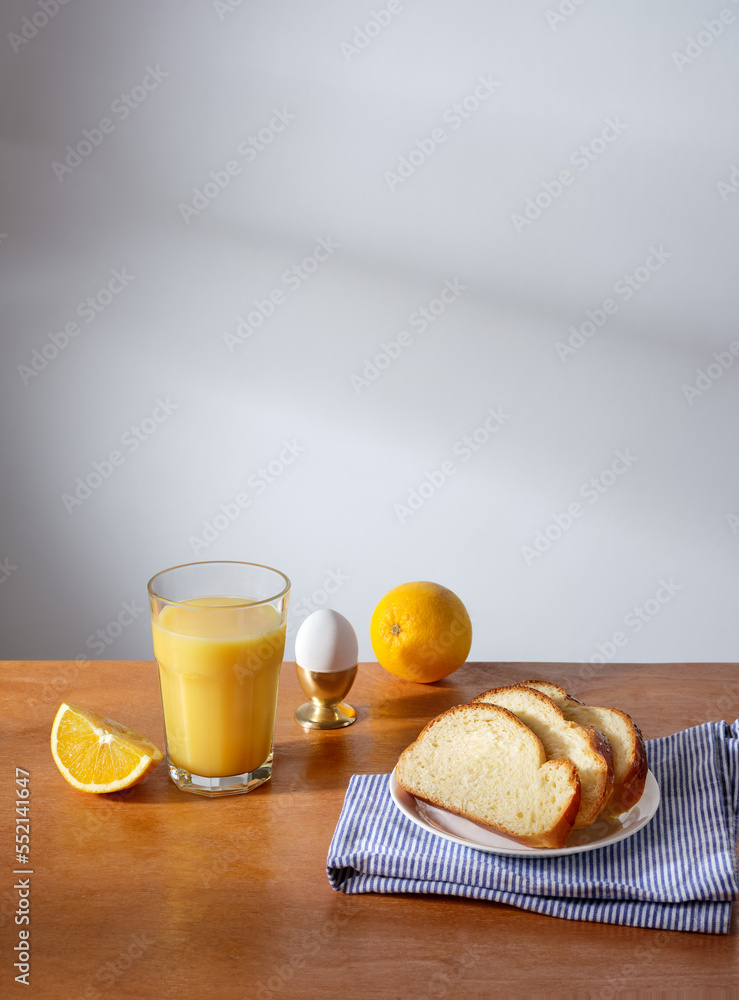 Sunny breakfast scene with a glass of freshly pressed orange juice, a boiled egg and some slices of brioche bread Sunny breakfast scene with a glass of freshly pressed orange juice, a boiled egg and some slices of brioche bread