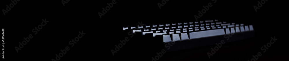 Modern trendy mechanical computer keyboard on a black background. Side view. Web banner. Copy space. Selective focus