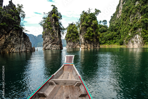 Wooden Thai traditional long tail boat on a lake with limestone mountains in Khao Sok National Park, Surat Thani Province, Thailand. Beautiful landscape. © neonshot