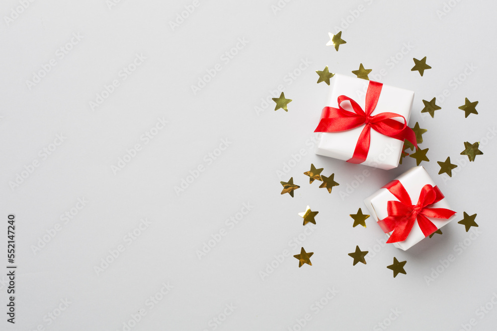 Gift boxes and stars confetti on color background, top view Gift boxes and stars confetti on color background, top view