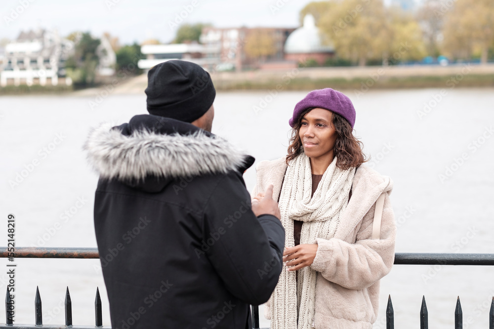 Impaired-hearing woman is in front of a friend who is using gesture to talk. Impaired-hearing woman is in front of a friend who is using gesture to talk.