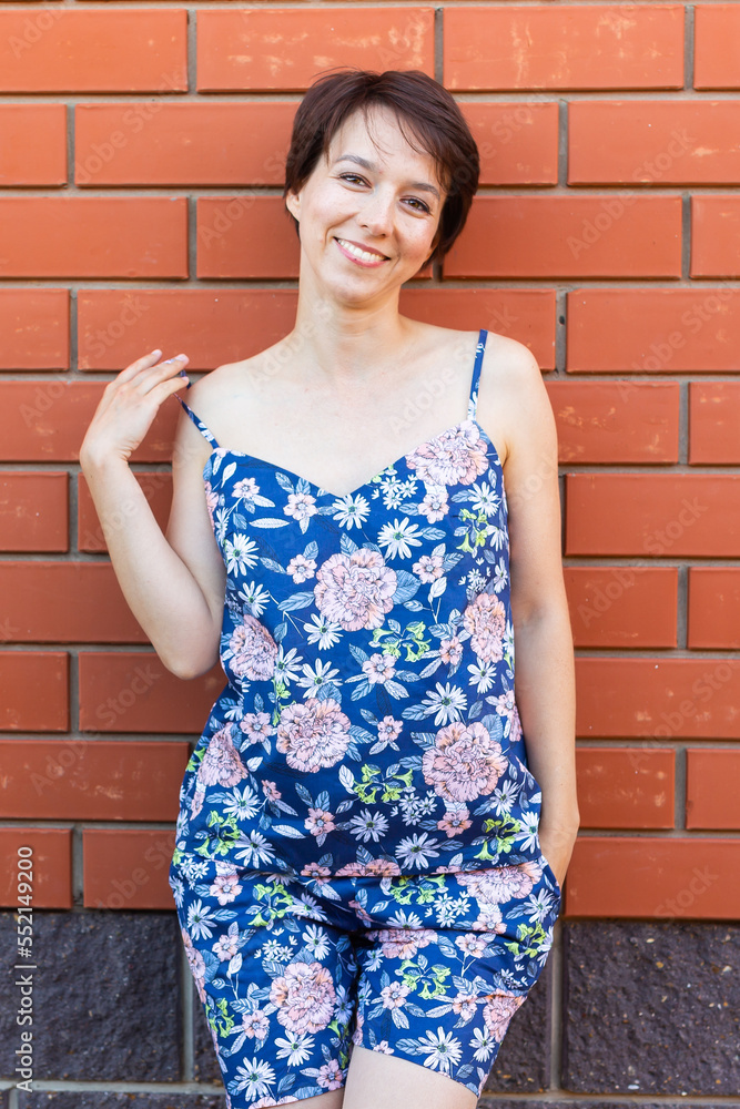 Cheerful woman in home wear pajama outdoor brick wall background emotions - sleepwear and homewear concept