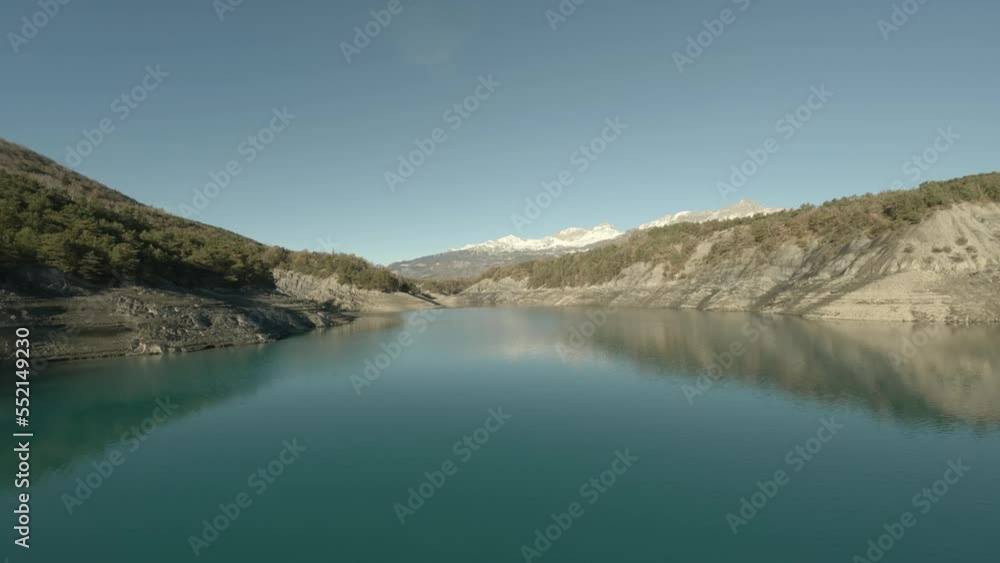 Stabilized view above the clear water of a lake bordered by forests in the Hautes-Alpes Stabilized view above the clear water of a lake bordered by forests in the Hautes-Alpes