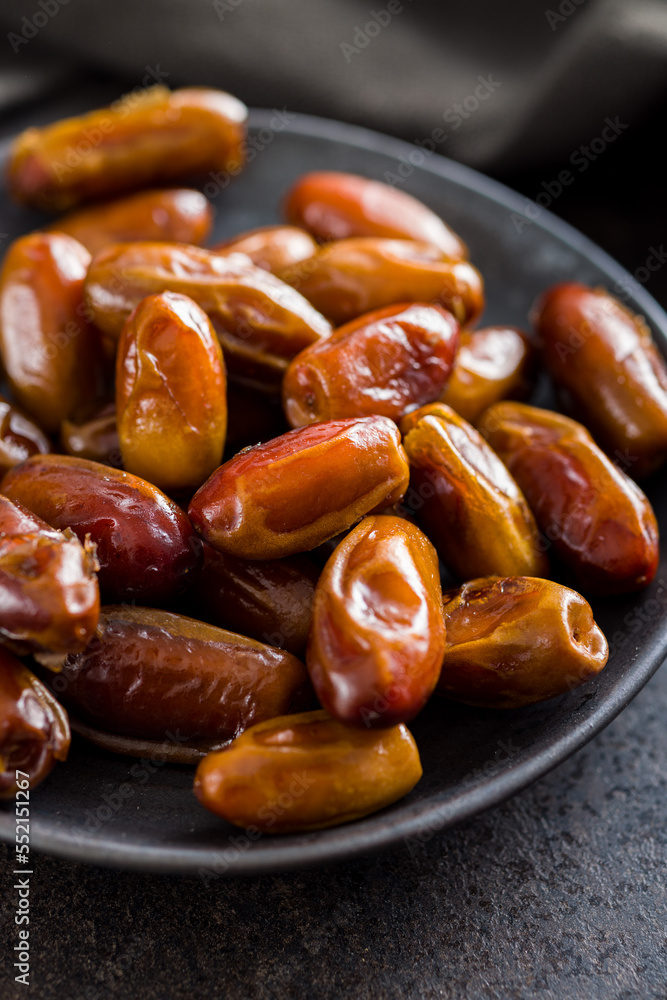 Dried dates fruit on plate on black table. Dried dates fruit on plate on black table.