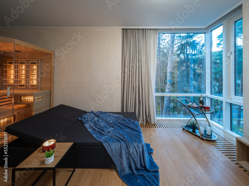 Wooden Finnish sauna in room of private house. Lounge zone. Coffee table with candle. Panorama window.