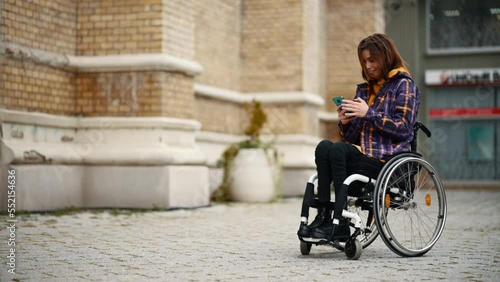  Woman with disability who uses a wheelchair using a smartphone in the city photo