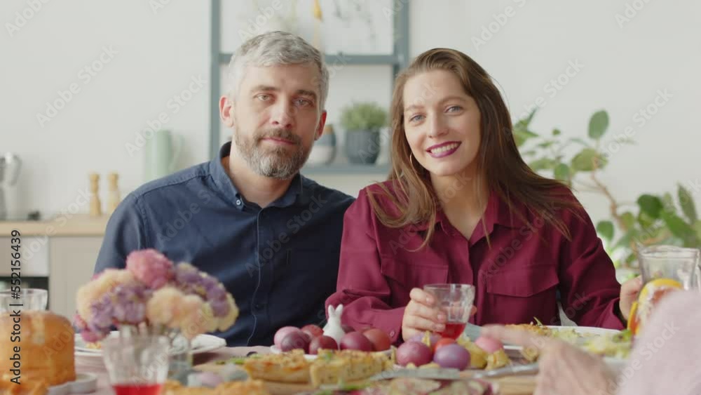 Portrait of beautiful couple posing for camera at dinner table while celebrating Easter with family Portrait of beautiful couple posing for camera at dinner table while celebrating Easter with family