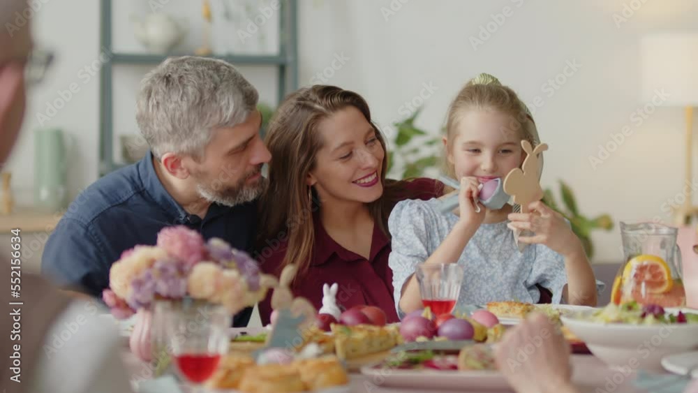 Family couple speaking with cute little daughter as she playing with toys on Easter dinner at home Family couple speaking with cute little daughter as she playing with toys on Easter dinner at home
