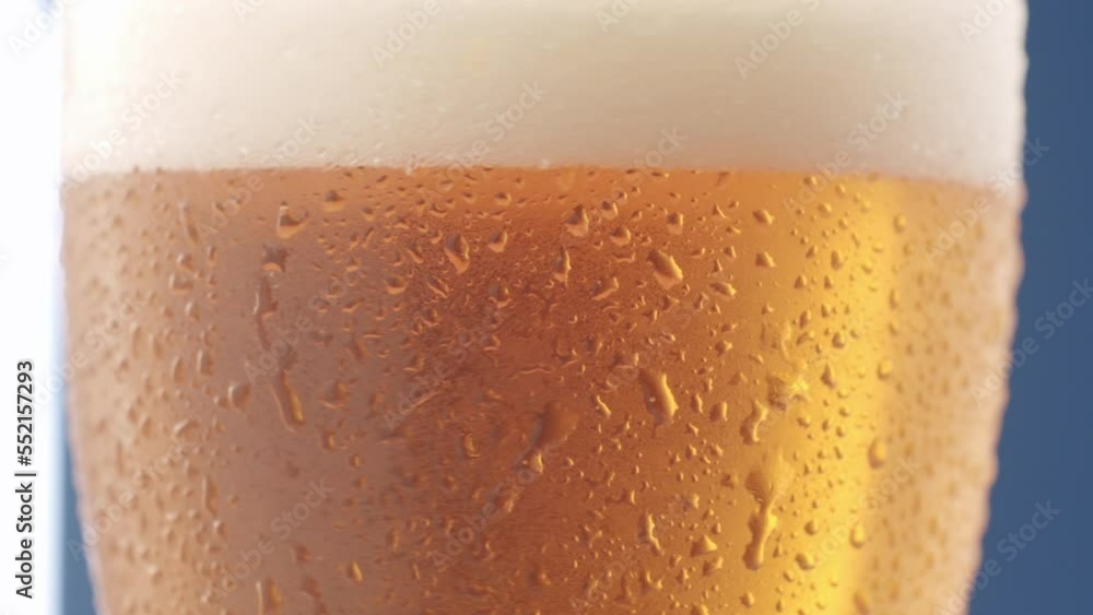 Wet glass of cold refreshing beer in studio. Closeup of water drops rolling on surface of transparent glass pint of cold refreshing beer with foam Wet glass of cold refreshing beer in studio. Closeup of water drops rolling on surface of transparent glass pint of cold refreshing beer with foam