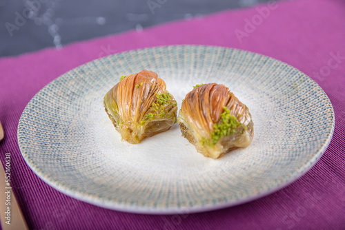 Slice of mussel baklava. Special Turkish baklava in the shape of mussels with pistachio on a ceramic plate. Islamic Eid Concept.