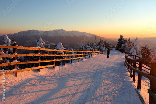 Amazing view of winter sunset over a slope in Poiana Brasov ski resort in Transylvania, Romania. Bucegi mountains in background.