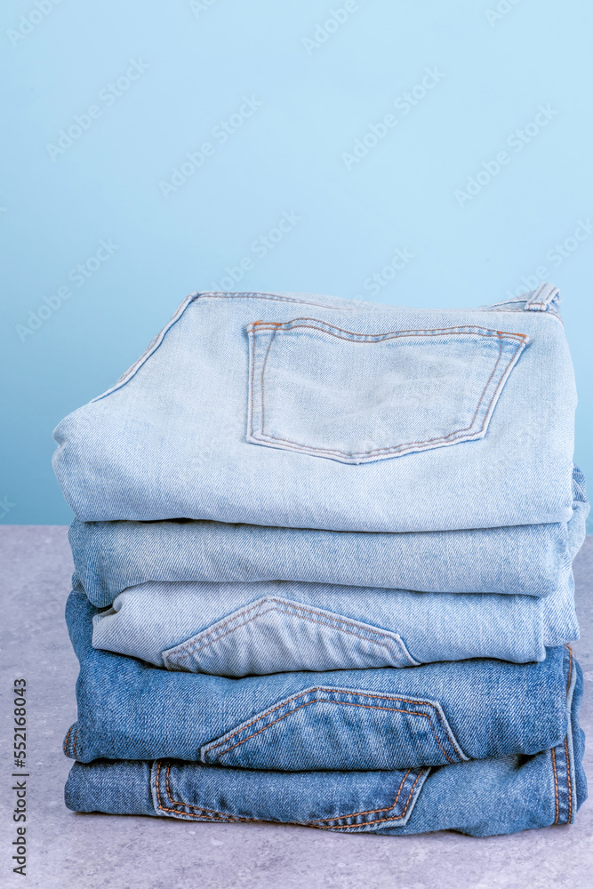Stack of jeans pants on blue background. Fast fashion concept Stack of jeans pants on blue background. Fast fashion concept