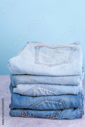 Obraz na płótnie Stack of jeans pants on blue background. Fast fashion concept