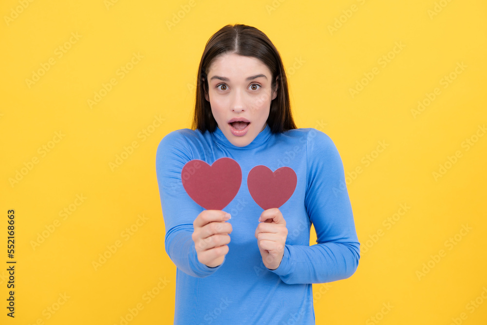 Girl feeling love. Portrait of attractive lovely cheerful girl holding in hands paper heart, isolated over yellow background. Love valentine concept. Girl feeling love. Portrait of attractive lovely cheerful girl holding in hands paper heart, isolated over yellow background. Love valentine concept.