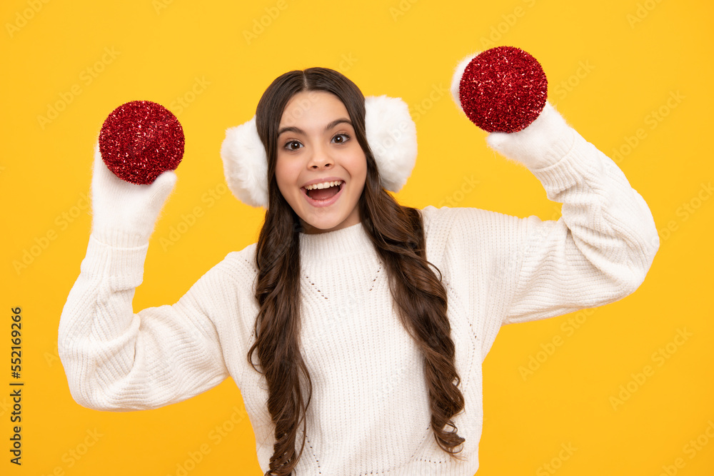 Portrait of teenager child girl wearing knitted gloves and winter sweater playing with christmas ball isolated on yellow studio background. Portrait of teenager child girl wearing knitted gloves and winter sweater playing with christmas ball isolated on yellow studio background.