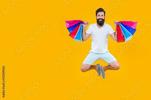 bearded man go shopping at sale, copy space. man jumping in studio with bags. shopping sale