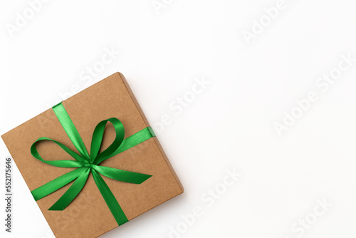 Flat lay of craft present box with green ribbon on the white background