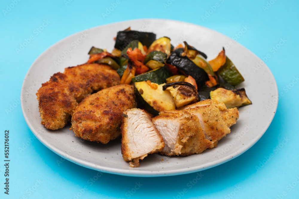 Delicious crispy fried breaded chicken breast strips with baked vegetables