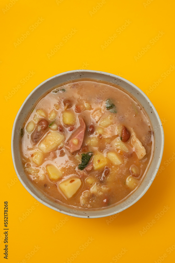 Sopa de pedra Portuguese Stone Soup with beans and sausages in the plate on yellow. Sopa de pedra Portuguese Stone Soup with beans and sausages in the plate on yellow.