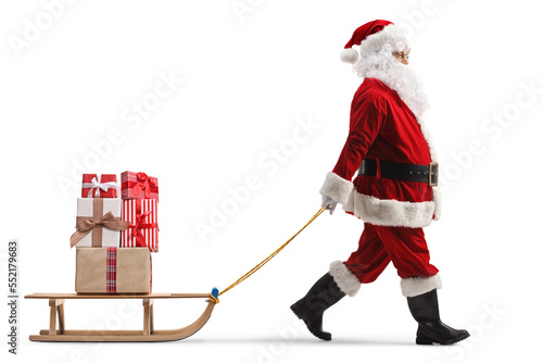 Obraz na plátne Full length profile shot of santa claus pulling a wooden sled with presents