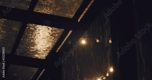 Torrential storm rain fall on transparent roof of terrace at night, static shot