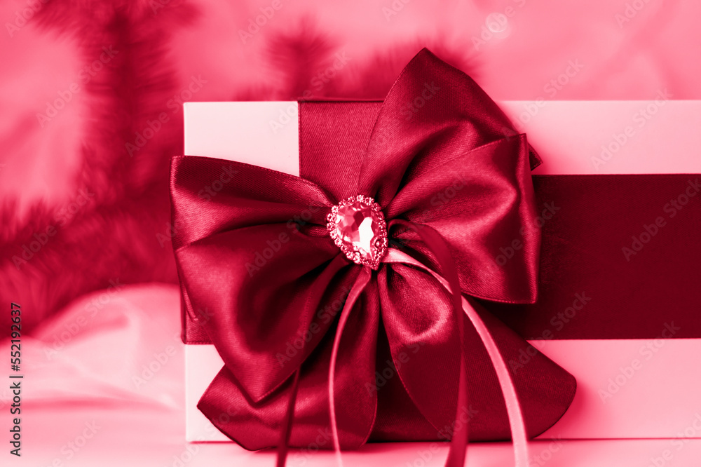 A Christmas gift decorated with a beautiful bow on a light background with a fir twig. Gifts, joy, surprise. Selective focus. the concept of Christmas and New Year. A Christmas gift decorated with a beautiful bow on a light background with a fir twig. Gifts, joy, surprise. Selective focus. the concept of Christmas and New Year.