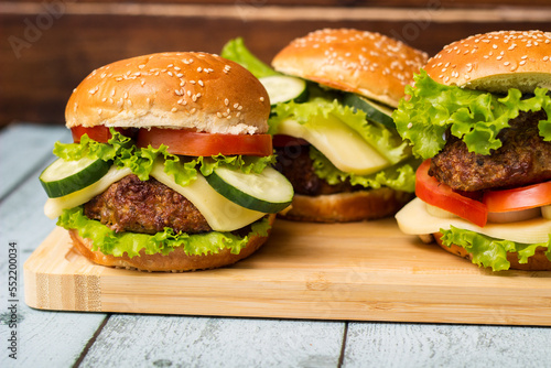 Delicious burgers with lettuce and cheese served on cutting board