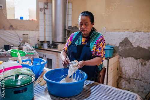 Mujer guatemalteca preparando tamalios en hoja de elote, un platillo tradicional de Guatemala.  photo