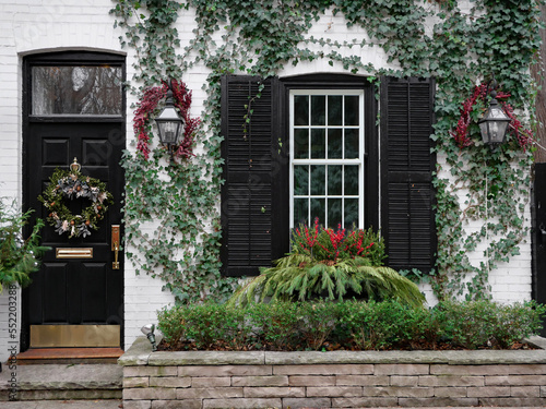 Front of old brick house with Christmas wreath on front door and holly berry decorations