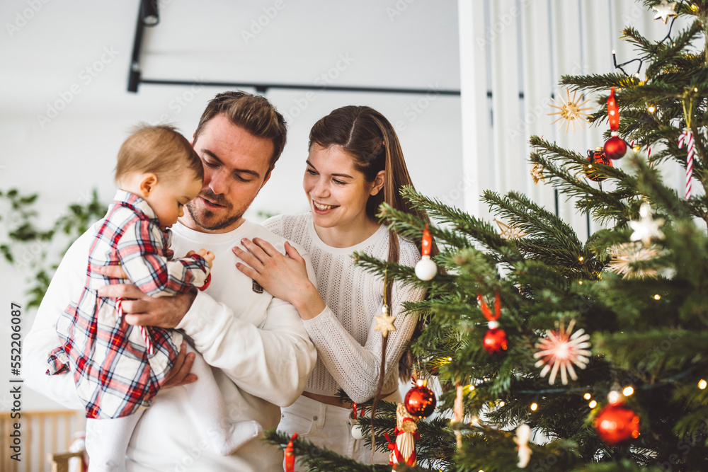 Family of three decorating the Christmas tree on Christmas day Family of three decorating the Christmas tree on Christmas day