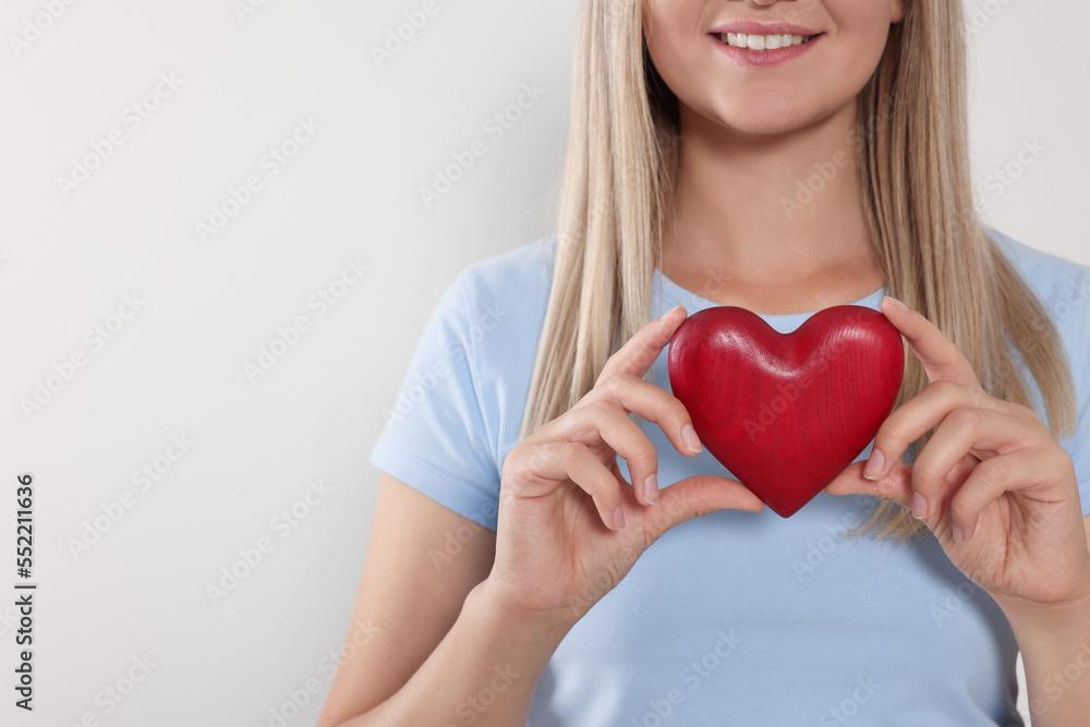 Happy volunteer holding red heart with hands on light background, closeup. Space for text Happy volunteer holding red heart with hands on light background, closeup. Space for text