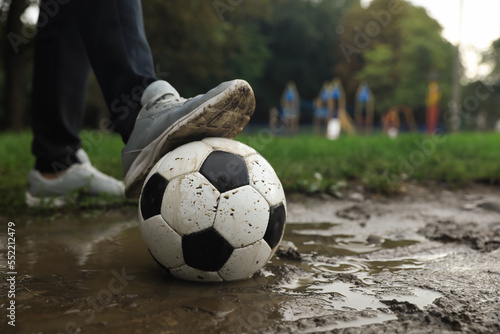 Man with dirty soccer ball in puddle outdoors, closeup © New Africa