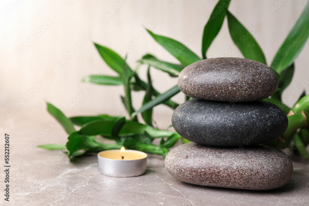 Obraz premium Stacked spa stones, bamboo and candle on light grey table. Space for text