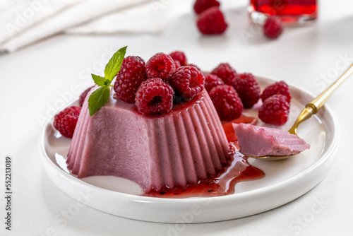 Foto Sliced raspberry panna cotta or jelly custard agar-agar pudding with fresh berries and sweet syrup on a plate