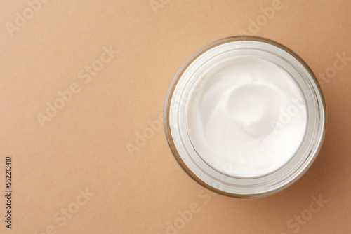 Jar of face cream on beige background  top view. Space for text