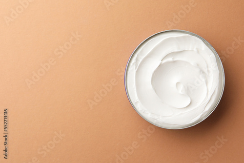 Jar of face cream on beige background, top view. Space for text