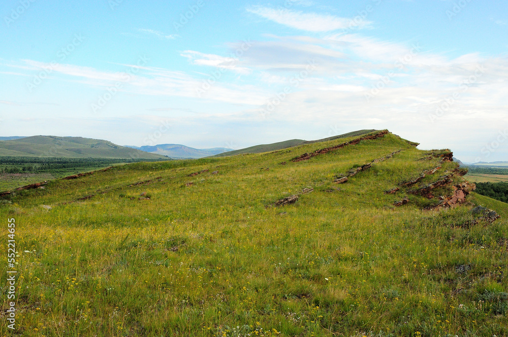 High hills with sheer cliffs in the endless steppe under a warm summer sky. High hills with sheer cliffs in the endless steppe under a warm summer sky.
