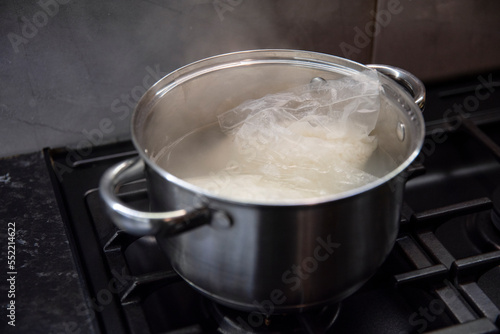 Woreczki z ryżem gotujące się w małym garnuszku na czarnej kuchence gazowej