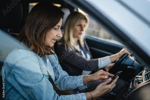 two women drive in car travel use smartphone for gps map location © Miljan Živković