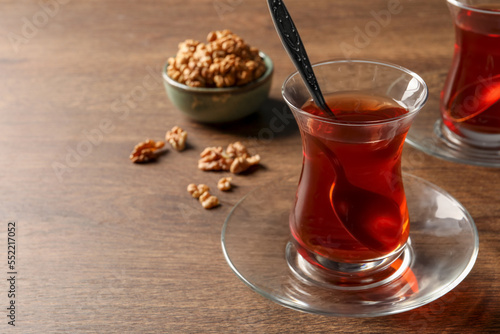 Glasses of traditional Turkish tea and walnuts on wooden table, closeup. Space for text