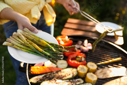 Woman cooking vegetables on barbecue grill outdoors, closeup