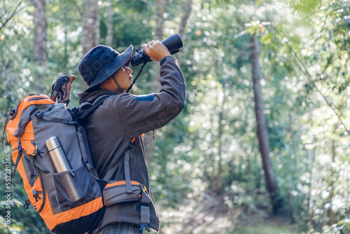 Wallpaper Mural Young male hiker with backpack holding binoculars looking on green forest Torontodigital.ca