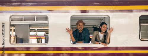 Couple asian traveller with bag on honeymoon travel by train Sticking head outta the window. Happy Man and woman near platform train station. Planning tourist on vacation time holiday weekend.