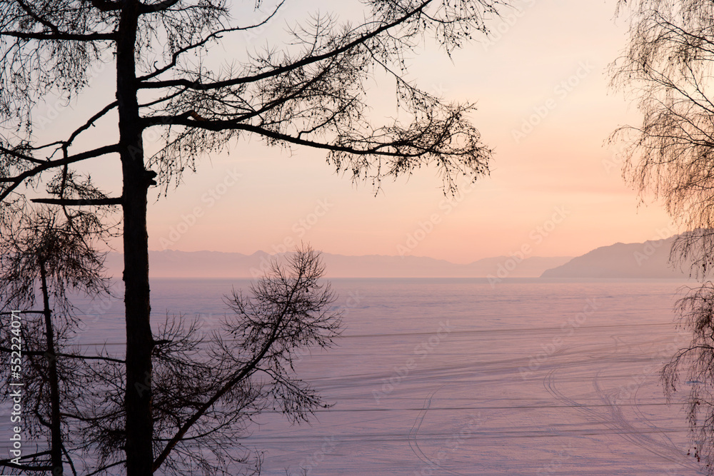 Silhouettes of Trees Against the Backdrop of a Sunset on a Frozen Winter Lake. Silhouettes of Trees Against the Backdrop of a Sunset on a Frozen Winter Lake.