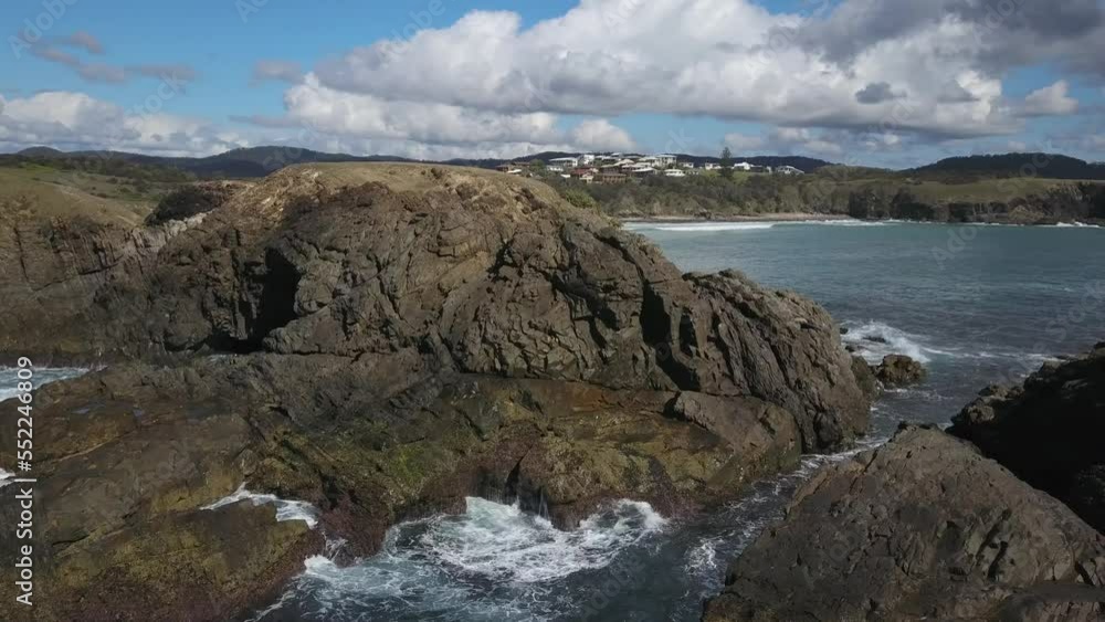 Aerial forward over rocky and jagged cliff with Emerald beach and Look-at-me-now Headland in background, Australia Aerial forward over rocky and jagged cliff with Emerald beach and Look-at-me-now Headland in background, Australia